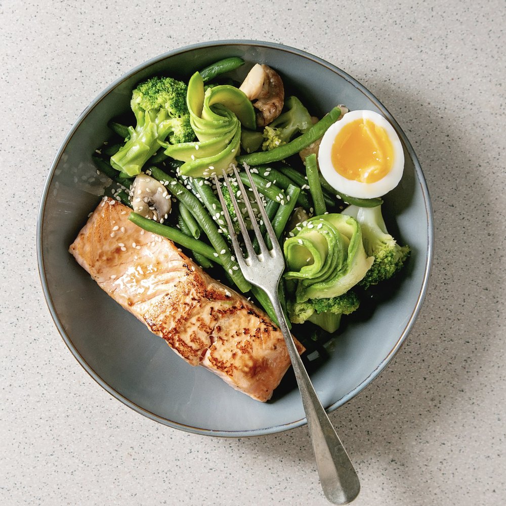 Bord met zalm, groene groenten en een zachtgekookt ei